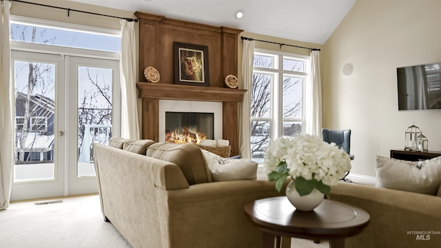 living area featuring light carpet, vaulted ceiling, visible vents, and a premium fireplace