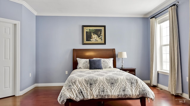 bedroom with visible vents, crown molding, baseboards, and wood finished floors