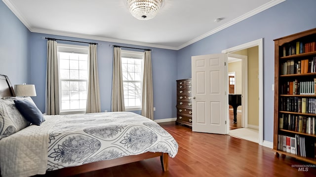 bedroom with ornamental molding, baseboards, and wood finished floors