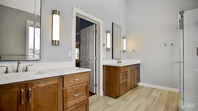 full bath with plenty of natural light, two vanities, a sink, and wood finished floors