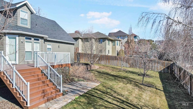 view of yard with a deck, a residential view, a fenced backyard, and stairway