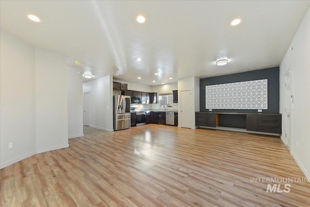 unfurnished living room featuring light wood-type flooring and sink