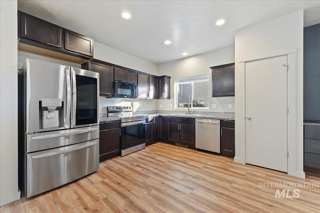 kitchen with appliances with stainless steel finishes, dark brown cabinetry, and light hardwood / wood-style floors