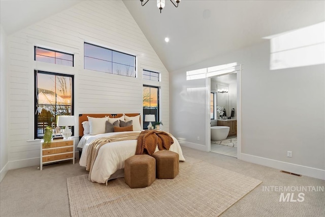 carpeted bedroom with ensuite bathroom and high vaulted ceiling