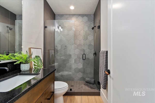 bathroom with walk in shower, vanity, toilet, and wood-type flooring