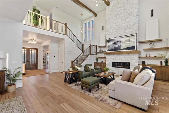 living room with french doors, a fireplace, light hardwood / wood-style floors, and beamed ceiling