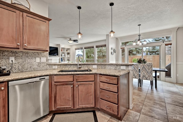 kitchen featuring decorative light fixtures, dishwasher, sink, kitchen peninsula, and light stone countertops