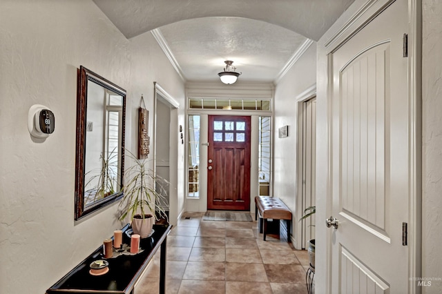 foyer entrance with ornamental molding and light tile patterned flooring