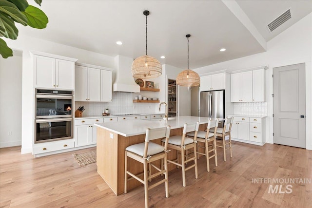 kitchen with premium range hood, a sink, visible vents, light countertops, and appliances with stainless steel finishes