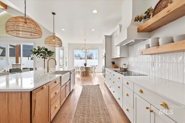 kitchen with open shelves, appliances with stainless steel finishes, a sink, light wood-type flooring, and premium range hood