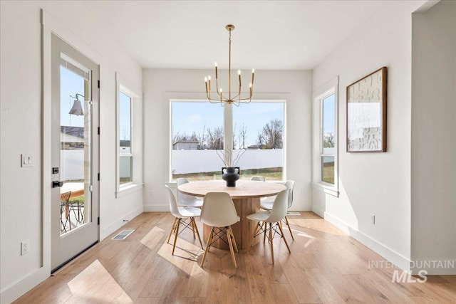 dining space featuring light wood-style floors, visible vents, baseboards, and an inviting chandelier