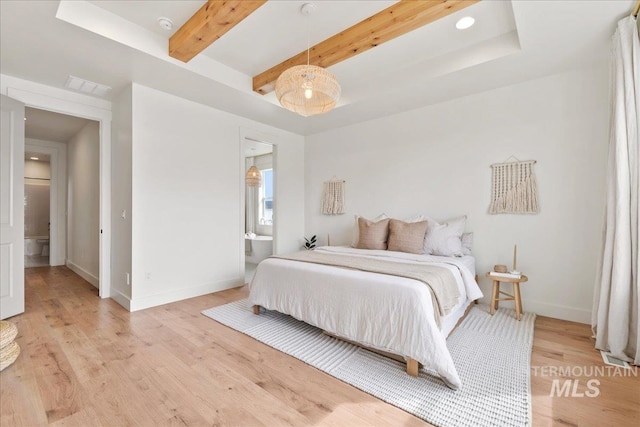 bedroom featuring light wood finished floors, baseboards, visible vents, ensuite bathroom, and beam ceiling