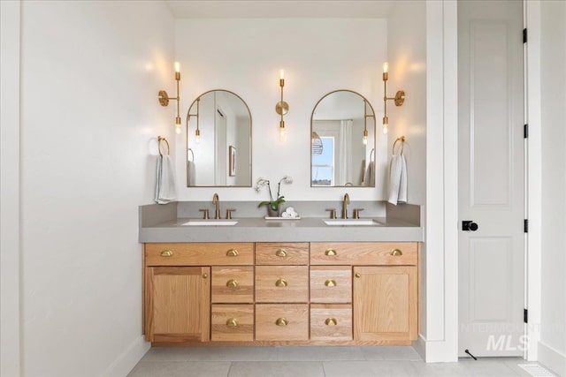 full bathroom with tile patterned flooring, a sink, baseboards, and double vanity