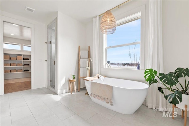 full bath featuring a stall shower, tile patterned flooring, a freestanding tub, and a healthy amount of sunlight