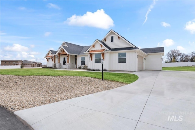 modern farmhouse featuring board and batten siding, a front yard, driveway, and fence