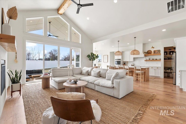 living room with visible vents, ceiling fan, light wood-style flooring, beamed ceiling, and high vaulted ceiling