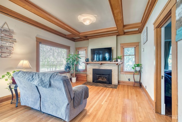 living area featuring a brick fireplace, coffered ceiling, baseboards, and wood finished floors