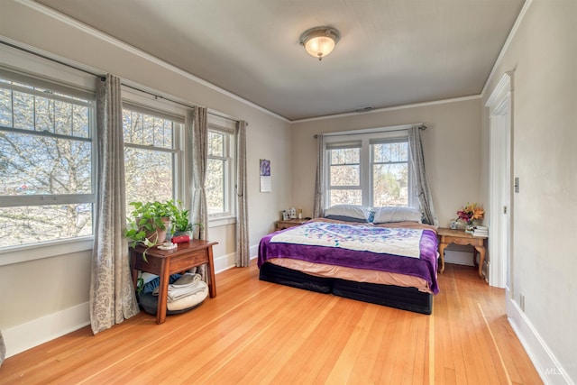 bedroom with baseboards, multiple windows, hardwood / wood-style floors, and crown molding