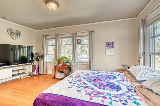 bedroom with visible vents, wood finished floors, and ornamental molding