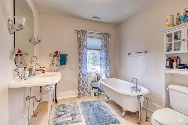 full bathroom with tile patterned floors, a freestanding tub, visible vents, toilet, and baseboards