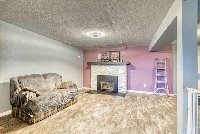 living room featuring a fireplace, wood finished floors, baseboards, and a textured ceiling