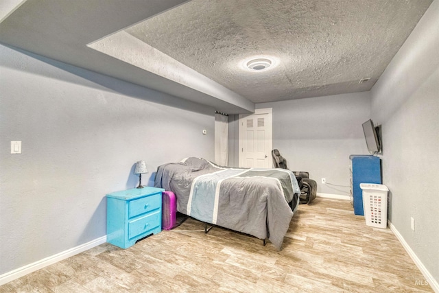 bedroom featuring wood finished floors, baseboards, and a textured ceiling