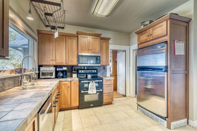 kitchen featuring backsplash, tile counters, light tile patterned floors, appliances with stainless steel finishes, and a sink