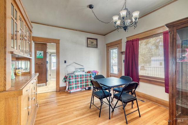 dining room with light wood-style flooring, a notable chandelier, visible vents, and ornamental molding