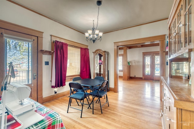 dining room with baseboards, a chandelier, ornamental molding, and light wood finished floors