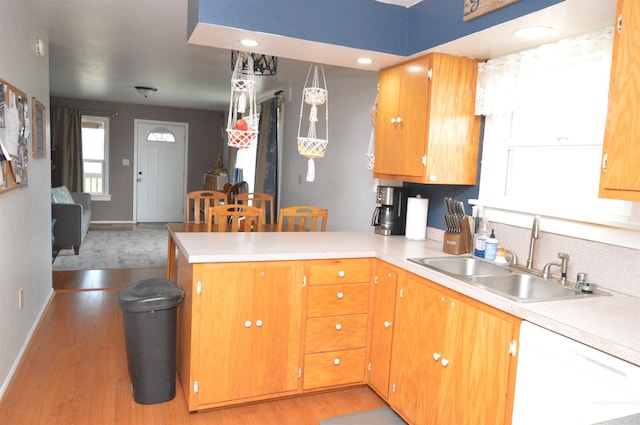 kitchen with sink, light hardwood / wood-style flooring, hanging light fixtures, white dishwasher, and kitchen peninsula