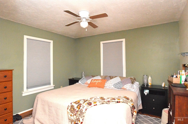 bedroom with ceiling fan and a textured ceiling