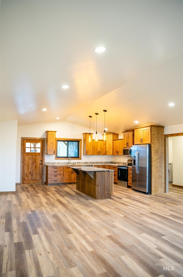 kitchen with vaulted ceiling, pendant lighting, light hardwood / wood-style floors, appliances with stainless steel finishes, and a kitchen breakfast bar