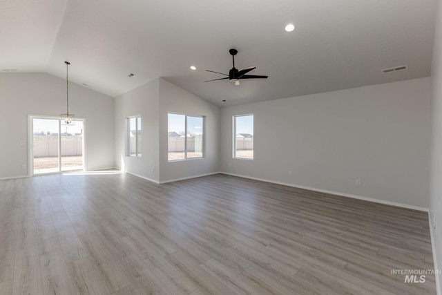 unfurnished living room featuring wood finished floors, baseboards, visible vents, vaulted ceiling, and ceiling fan with notable chandelier