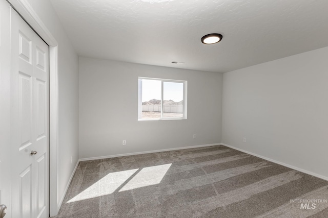 carpeted empty room with visible vents and baseboards