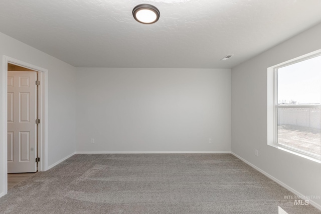 unfurnished room featuring light carpet, a textured ceiling, and baseboards