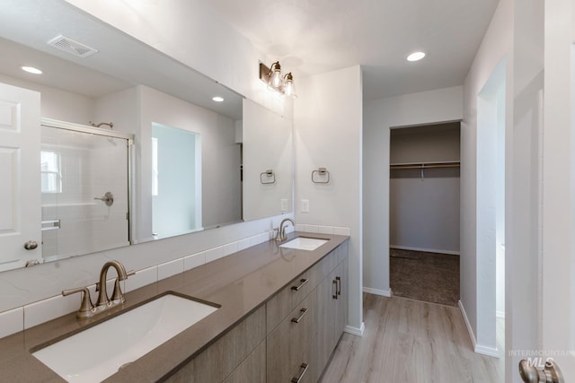 bathroom featuring a walk in closet, a shower stall, visible vents, and a sink