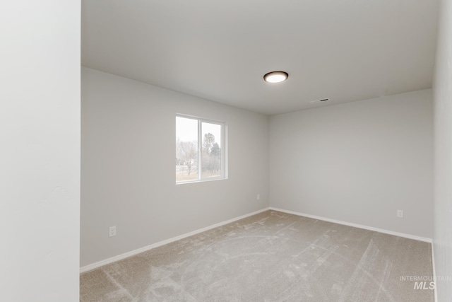 empty room with baseboards, light carpet, and visible vents