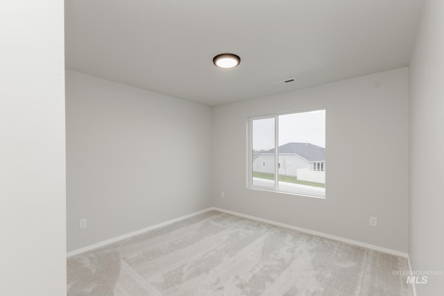 empty room featuring light colored carpet, visible vents, and baseboards