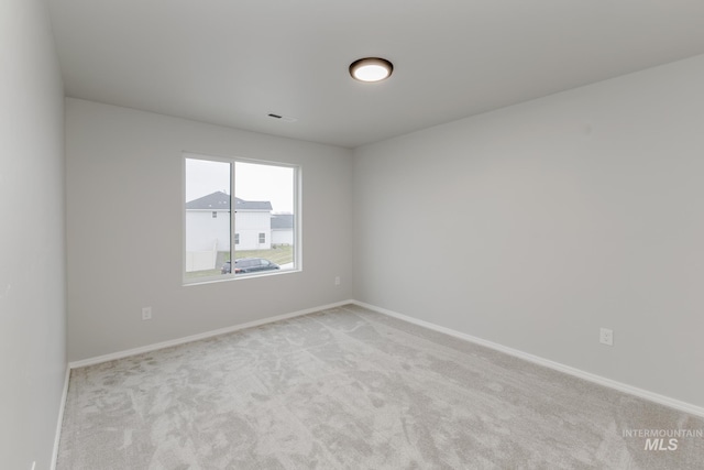 spare room with visible vents, baseboards, and light colored carpet