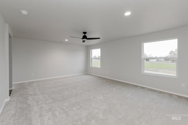 spare room with light colored carpet, baseboards, and ceiling fan