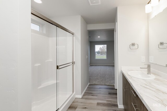 bathroom with vanity, wood finished floors, visible vents, and a stall shower