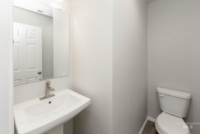 bathroom featuring a sink, visible vents, baseboards, and toilet