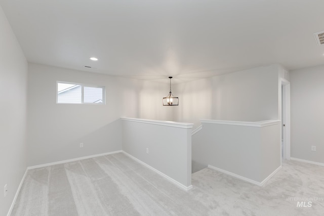 unfurnished room featuring a notable chandelier, light colored carpet, visible vents, and baseboards