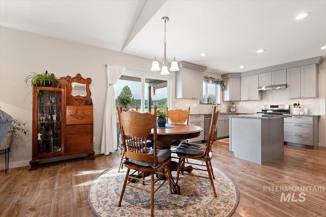 dining space with light wood-style floors, recessed lighting, and an inviting chandelier