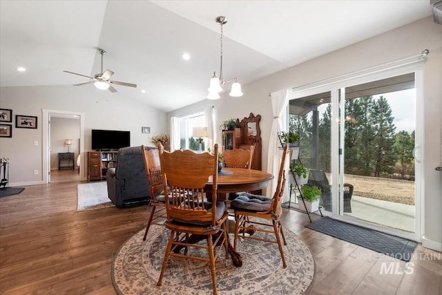 dining space with baseboards, wood finished floors, ceiling fan with notable chandelier, vaulted ceiling, and recessed lighting