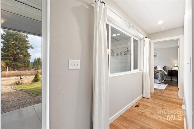 hallway with light wood-type flooring and baseboards