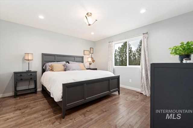 bedroom with baseboards, wood finished floors, and recessed lighting