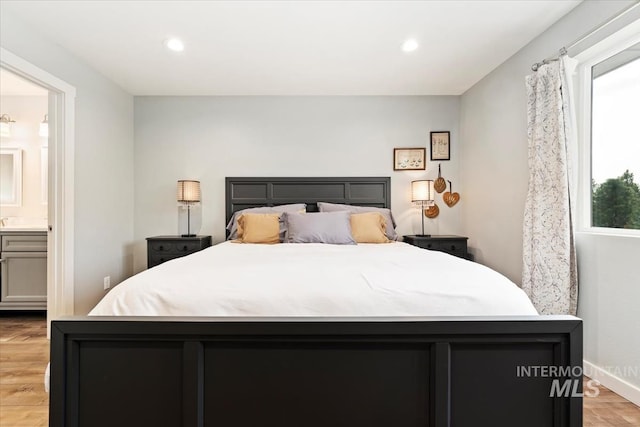 bedroom with light wood-style floors, ensuite bath, baseboards, and recessed lighting