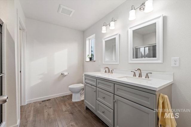 bathroom with double vanity, wood finished floors, a sink, and visible vents