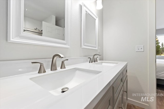 bathroom with a sink, double vanity, ensuite bath, and baseboards